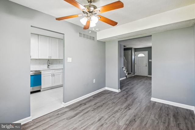 interior space featuring a ceiling fan, visible vents, a sink, baseboards, and light wood finished floors