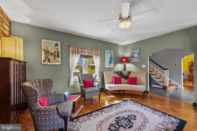 living area featuring stairway, baseboards, and a ceiling fan