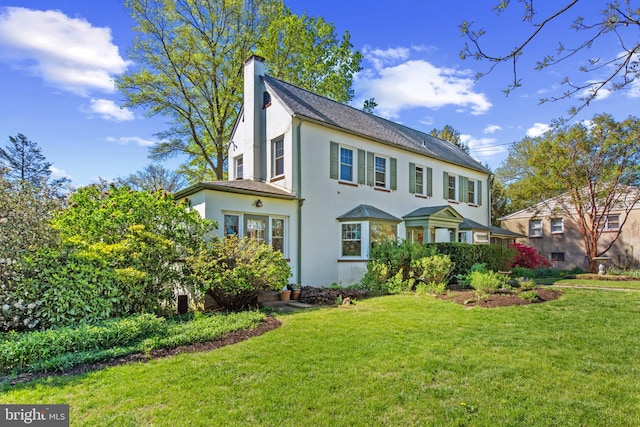 view of front of house with a chimney, a front lawn, and stucco siding