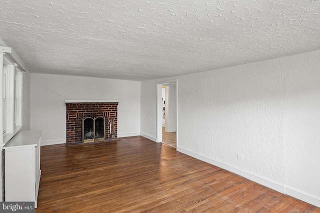 unfurnished living room featuring a textured ceiling, wood finished floors, baseboards, and a fireplace