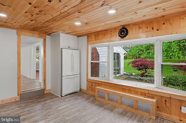 kitchen featuring freestanding refrigerator, radiator, plenty of natural light, white cabinetry, and recessed lighting