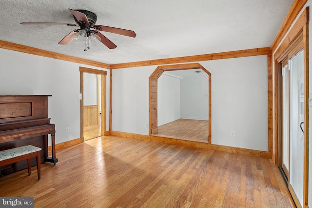bonus room with baseboards, wood finished floors, ceiling fan, a textured ceiling, and arched walkways