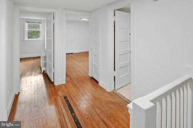 hall featuring light wood-style flooring and baseboards