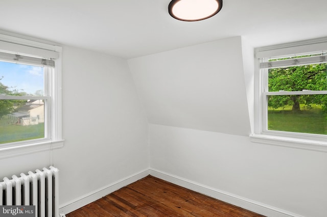 empty room featuring radiator heating unit, dark wood-style flooring, healthy amount of natural light, and baseboards