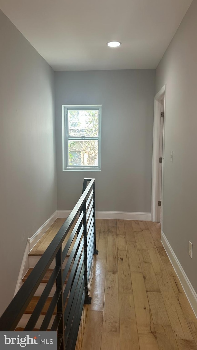 corridor with wood-type flooring, recessed lighting, baseboards, and an upstairs landing