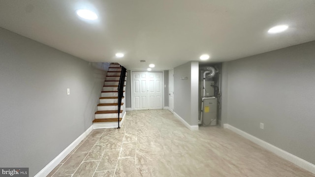 finished below grade area featuring stairs, recessed lighting, baseboards, and heating unit