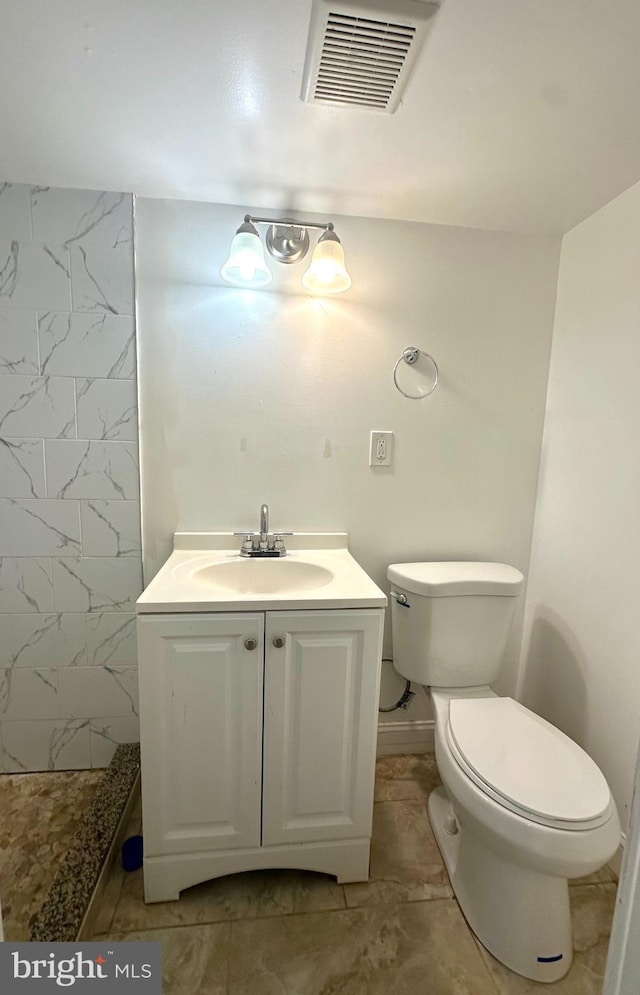 bathroom with walk in shower, vanity, toilet, baseboards, and visible vents