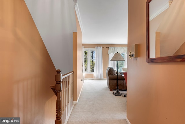 hallway featuring baseboards, an upstairs landing, and carpet flooring