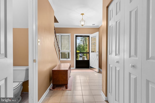doorway to outside with light tile patterned flooring, crown molding, and baseboards
