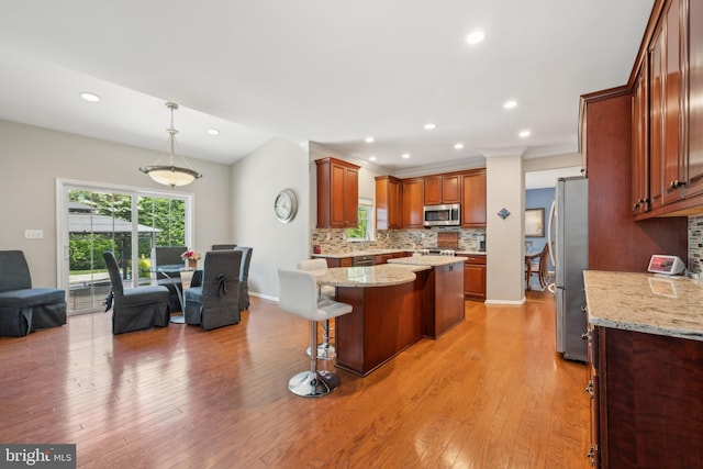 kitchen with a breakfast bar area, a center island, stainless steel appliances, recessed lighting, and tasteful backsplash