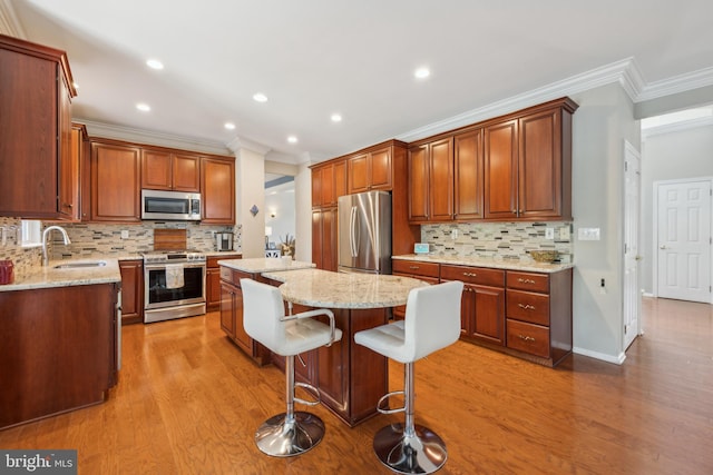kitchen with a center island, a sink, light wood-style flooring, and appliances with stainless steel finishes