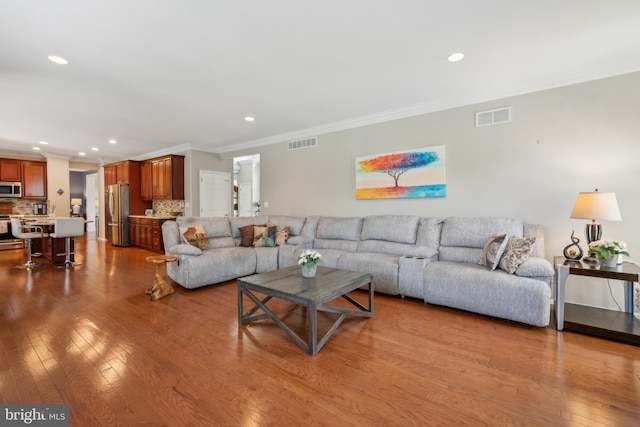 living room with visible vents, ornamental molding, wood finished floors, and recessed lighting