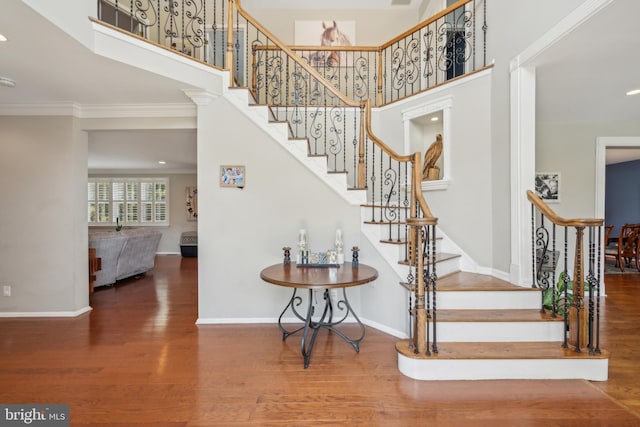 staircase featuring recessed lighting, baseboards, ornamental molding, and wood finished floors