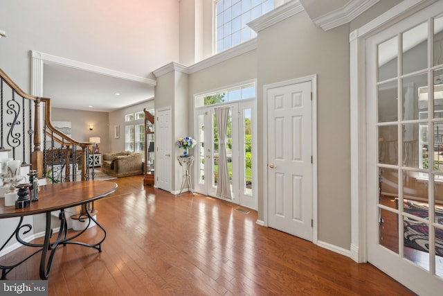 foyer featuring wood-type flooring, baseboards, stairs, and a high ceiling
