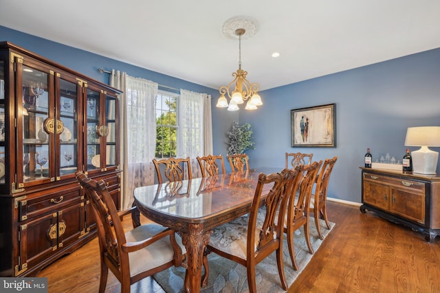 dining room with baseboards, wood finished floors, and a notable chandelier