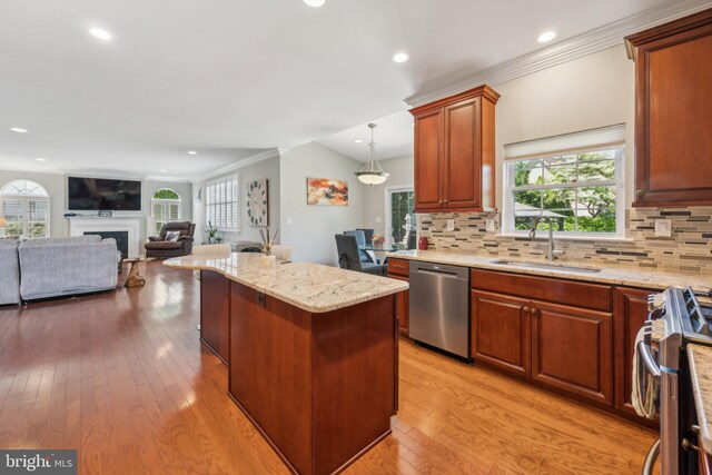 kitchen featuring a kitchen island, light stone countertops, open floor plan, a sink, and appliances with stainless steel finishes