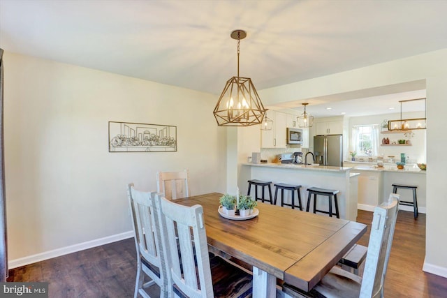 dining area with baseboards, dark wood-type flooring, and a chandelier