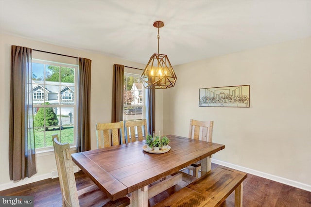 dining area with baseboards, a notable chandelier, and dark wood-style floors