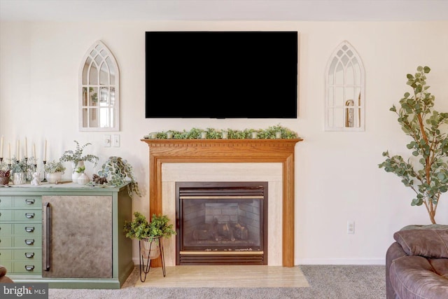 carpeted living room featuring baseboards and a glass covered fireplace