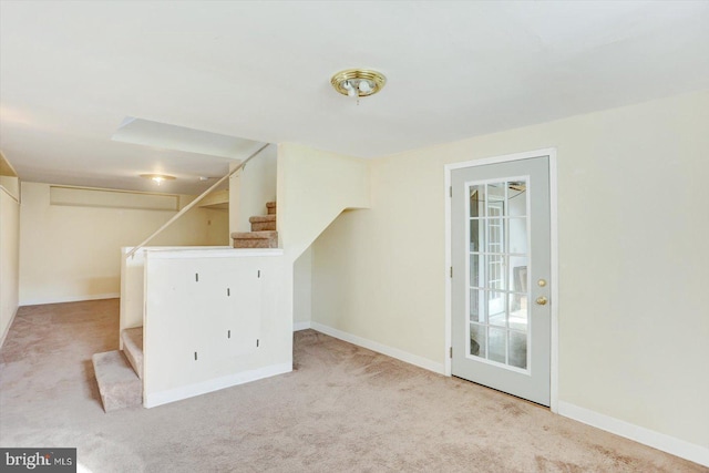 carpeted empty room featuring baseboards and stairway