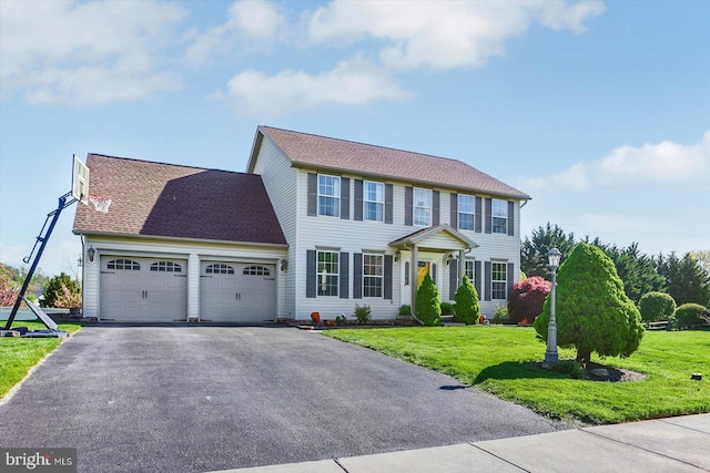 colonial house featuring a garage, a front lawn, aphalt driveway, and a shingled roof