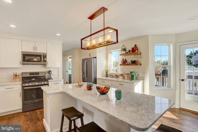 kitchen with white cabinets, appliances with stainless steel finishes, dark wood-style floors, and a kitchen breakfast bar