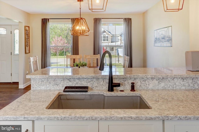 kitchen featuring a sink, white cabinetry, wood finished floors, and a chandelier