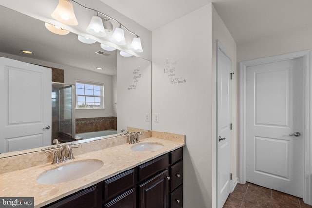 bathroom with double vanity, visible vents, a stall shower, and a sink