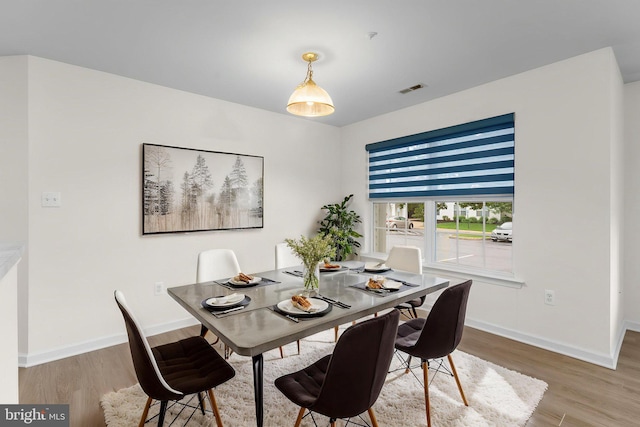 dining room featuring visible vents, wood finished floors, and baseboards