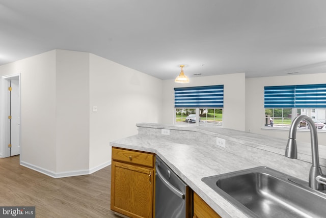 kitchen featuring a sink, brown cabinets, dishwasher, light wood finished floors, and baseboards