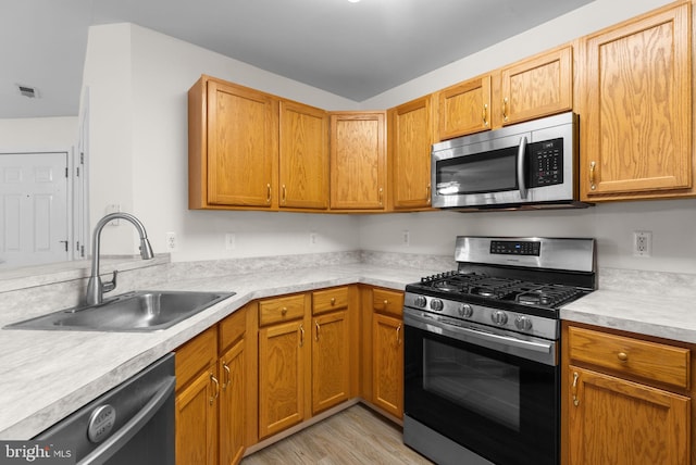 kitchen with light wood-style flooring, visible vents, a sink, light countertops, and appliances with stainless steel finishes