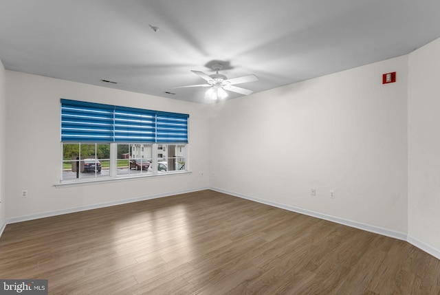 empty room with a ceiling fan, baseboards, visible vents, and wood finished floors