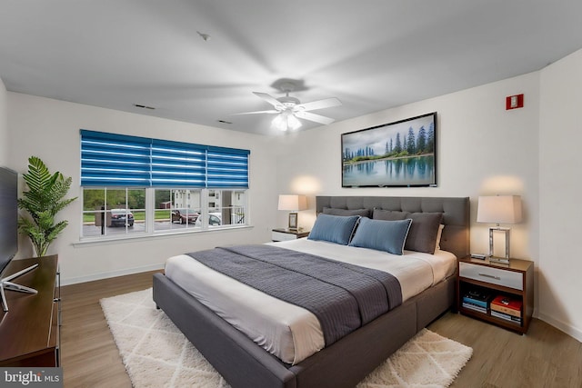 bedroom featuring wood finished floors, visible vents, baseboards, and a ceiling fan
