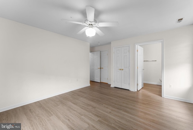 unfurnished bedroom with baseboards, ceiling fan, visible vents, light wood-style floors, and multiple closets