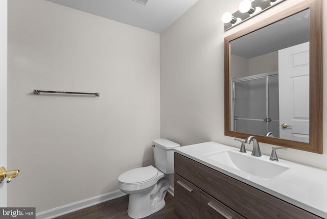 full bath featuring baseboards, toilet, vanity, wood finished floors, and an enclosed shower