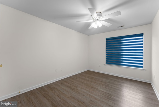 empty room with a ceiling fan, baseboards, visible vents, and wood finished floors