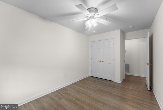unfurnished bedroom featuring baseboards, a closet, visible vents, and wood finished floors