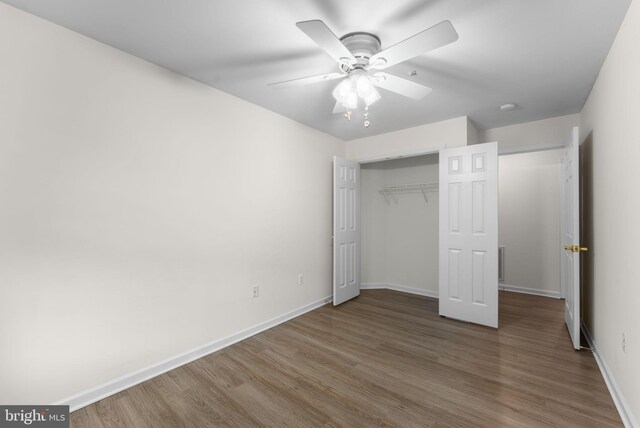 unfurnished bedroom featuring baseboards, a closet, ceiling fan, and wood finished floors