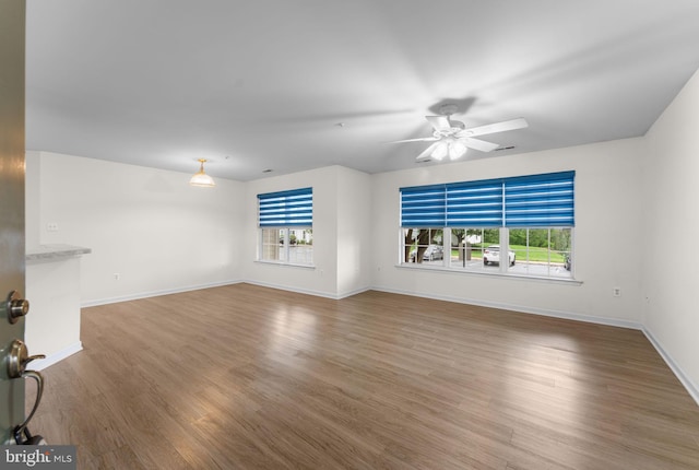unfurnished living room with ceiling fan, baseboards, plenty of natural light, and wood finished floors