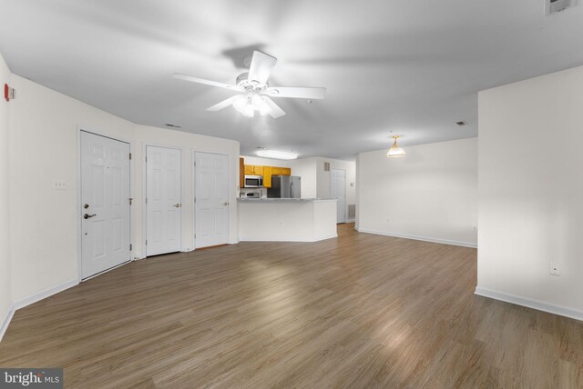 unfurnished living room with light wood finished floors, visible vents, baseboards, and a ceiling fan