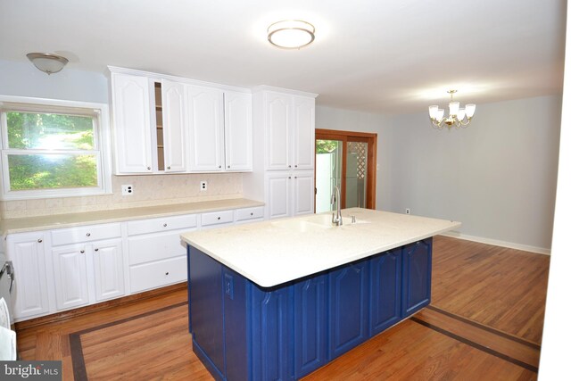 kitchen featuring a sink, white cabinetry, blue cabinetry, and a chandelier