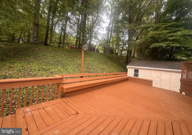 wooden deck with a storage unit, an outbuilding, and view of wooded area