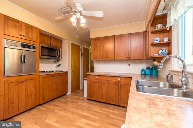 kitchen featuring open shelves, a sink, light wood-style flooring, stainless steel microwave, and tasteful backsplash