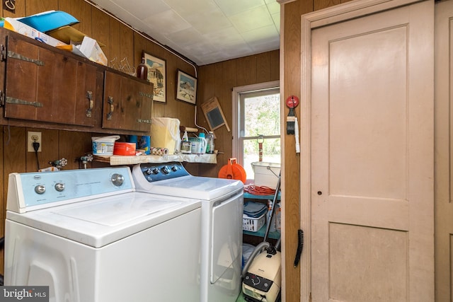 laundry room featuring cabinet space, wood walls, and washing machine and dryer