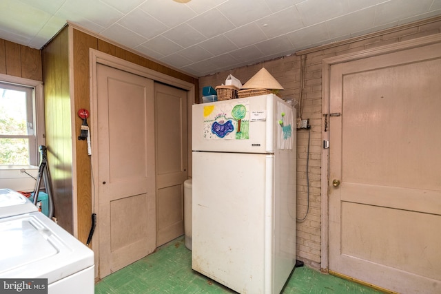 clothes washing area featuring independent washer and dryer, laundry area, wood walls, and tile patterned floors