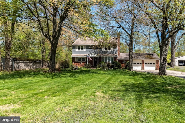 view of front of property with a front lawn, a chimney, brick siding, an attached garage, and driveway
