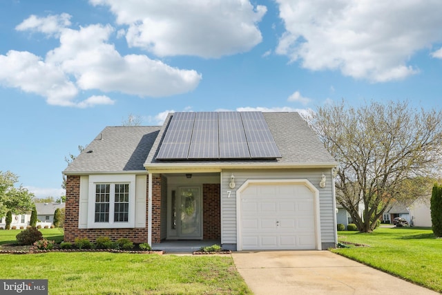 view of front facade with brick siding, a garage, roof mounted solar panels, a front yard, and concrete driveway