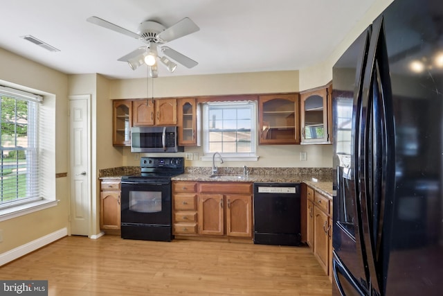 kitchen featuring black appliances, a sink, brown cabinetry, and visible vents