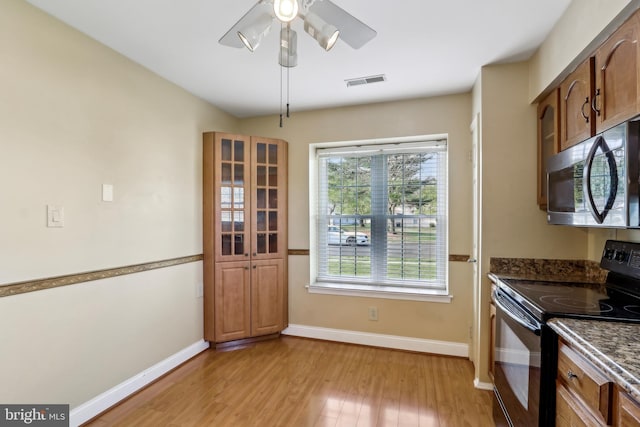 kitchen featuring stainless steel microwave, black electric range oven, visible vents, light wood-style flooring, and baseboards