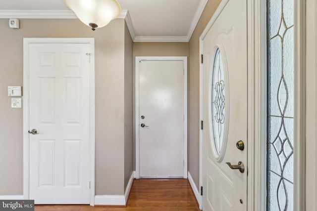 foyer entrance featuring wood finished floors, ornamental molding, and baseboards
